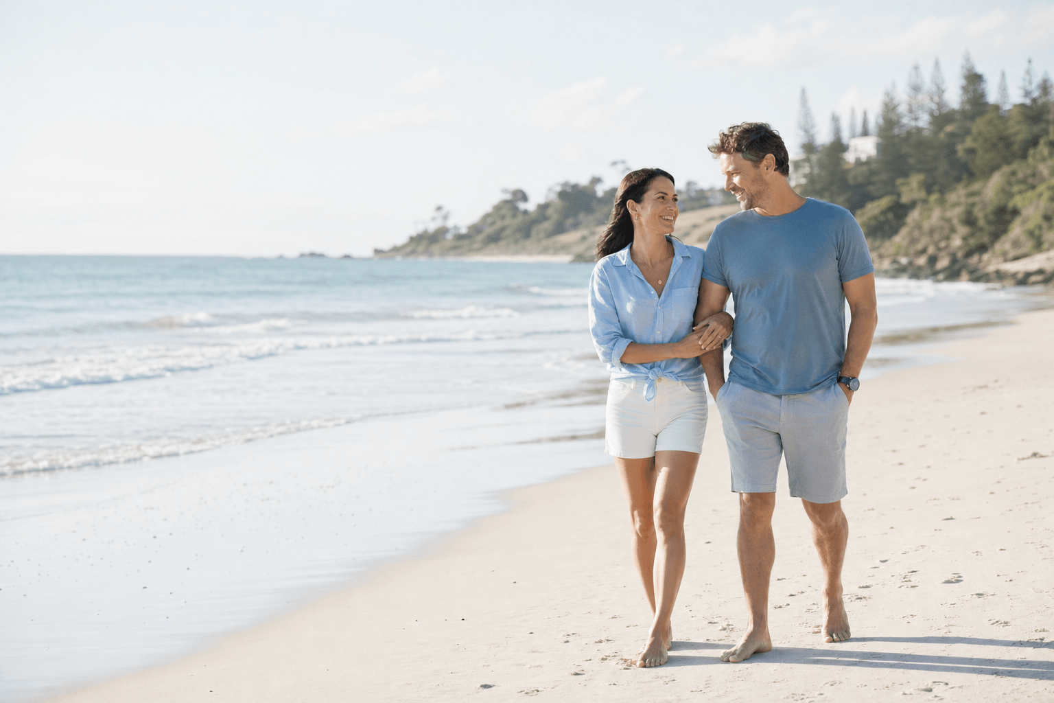 Australian couple walking together along a sunlit beach